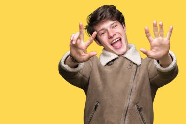 Gösterilen arka plan üzerinde kış ceket giyen genç yakışıklı adam izole ve parmakları ile işaret kendinden emin ve mutlu gülümseyerek süre 8 numaralı.