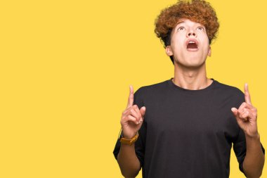 Siyah t-shirt giyen afro saçlı yakışıklı delikanlı hayrete ve yukarıya bakıyor ve parmakları ile işaret ve silah kaldırdı şaşırttı.