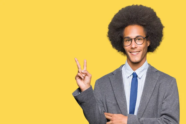 眼鏡をかけて勝利のサインを行うカメラでウィンクしている幸せそうな顔を浮かべてアフロの髪の若いアフリカ系アメリカ人ビジネスマン2 — ストック写真