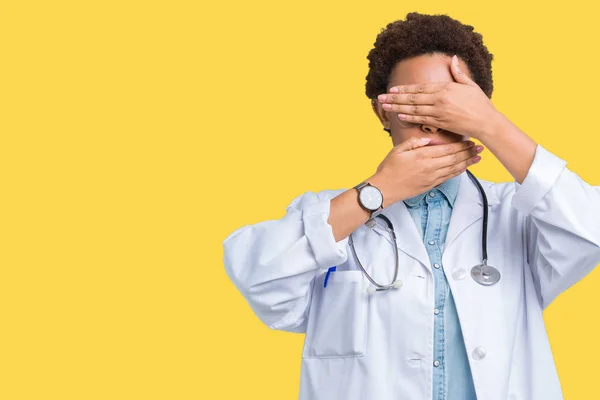 孤立した背景は 目を覆っていると手と口の上医療のコートを着ている若いアフリカ系アメリカ人医師女性は驚きし ショックを受けた 感情を隠す — ストック写真