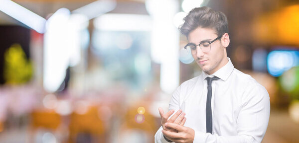 Young business man wearing glasses over isolated background Suffering pain on hands and fingers, arthritis inflammation