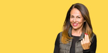 Kış yelek giyen güzel orta yaş kadın beckoning burada el mutlu ve gülümseyen davet ile jest geliyor