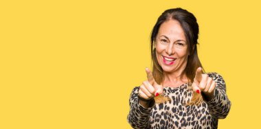 Güzel orta yaş kadın giyiyor leopar hayvan desenli sen ve kameraya gülümseyen pozitif ve neşeli parmaklarıyla işaret elbise