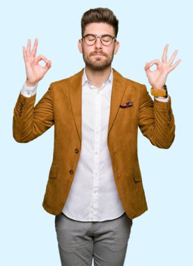 Genç yakışıklı iş adam gözlük rahatla ve gülümseyen gözlerle kapalı parmak jestle meditasyon yapıyor. Yoga kavramı.