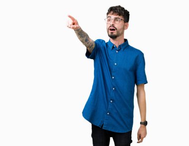 Yakışıklı delikanlı üzerinde gözlük takan izole arka plan ile sürpriz devam parmakla, açık ağız hayret ifadesi, önünde bir şey