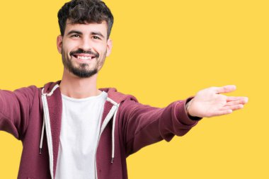 Yakışıklı delikanlı sarılmak için kollarını açarak gülümseyerek kameraya bakarak izole arka plan üzerinde. Neşeli ifade kucaklayan mutluluk.