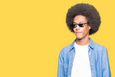 Afro saç ile genç Afrikalı Amerikalı adam gangster yaşam gözlükleri yüzüne gülümseme ile yan bakarak, doğal ifade giyiyor. Güven gülüyor.
