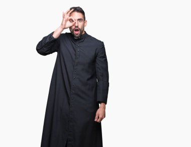 Genç Hıristiyan rahip ok jest sürpriz yüz, göz parmaklarının arasından seyir şok yapıyor izole arka plan üzerinde. İmansız ifade.