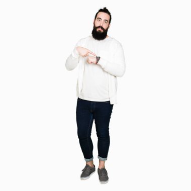 Uzun saç ve sakal acele saat, sabırsızlık, üzgün ve kızgın son tarih gecikme için izlemek için işaret sportif sweatshirt giyen genç hipster adamla