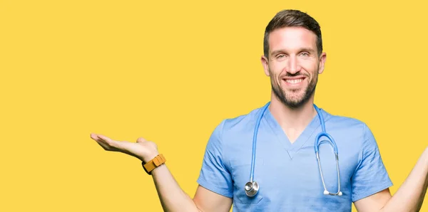 英俊的医生穿医疗制服在孤立的背景微笑显示双手张开手掌 呈现和广告比较和平衡 — 图库照片