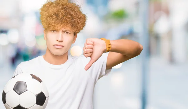 Jovem Homem Bonito Segurando Bola Futebol Com Cara Irritada Sinal — Fotografia de Stock