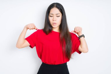 İzole arka planda kırmızı t-shirt giyen güzel esmer kadın reklam, sürpriz yüz ve açık ağız gösteren parmaklarla aşağı Işaret