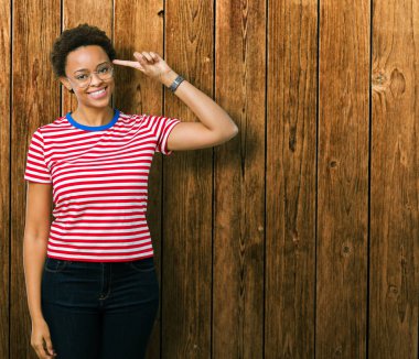 Güzel genç Afro-Amerikan kadın gözlük izole üzerinde bir parmak, harika bir fikir ya da düşünce, iyi hafıza ile baş gösteren gülen arka plan