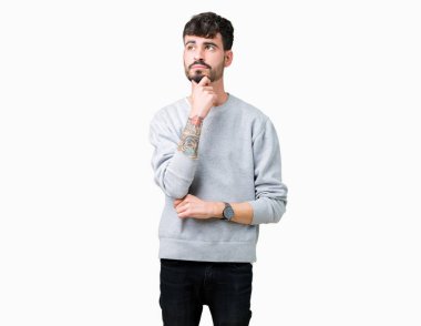 Çene düşünme hakkında soru, dalgın ifade üzerine el ile izole arka plan üzerinde sweatshirt giyen genç yakışıklı adam. Düşünceli yüzüyle gülümsüyor. Şüphe kavramı.