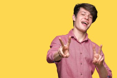 Genç yakışıklı iş adamı zafer işareti yapıyor parmak gösterilen kamera seyir gülümseyen izole arka plan üzerinde. İki numaralı.