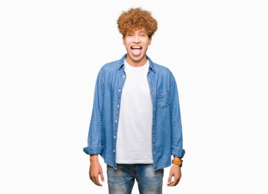 Genç yakışıklı adam ile afro saç giyen denim ceket yapıştırma dil dışarı mutlu ile komik ifade. Duygu konsepti.