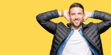 Yakışıklı adam giyen kış ceket dinlenirken ve germe kollar ve eller baş ve boyun arkasında ile mutlu gülümseyerek