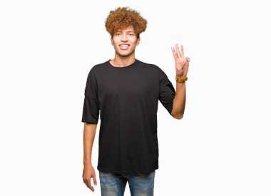 Afro saç ile genç yakışıklı adam siyah t-shirt gösteren ve parmak sayısı üç ile işaret kadar kendine güvenen ve mutlu gülümseyen.