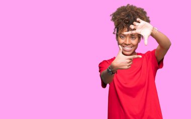Güzel genç Afro-Amerikan kadın elle yapma çerçeve ve parmakları ile mutlu yüz gülümseyen izole arka plan yüzünden. Yaratıcılık ve Fotoğrafçılık kavramı.