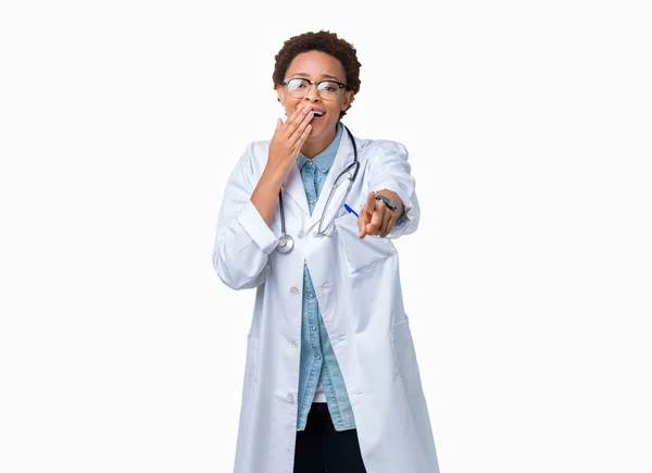 年轻的非洲医生妇女穿着医疗外套在孤立的背景笑你 指着相机用手指交口 羞耻表情 — 图库照片
