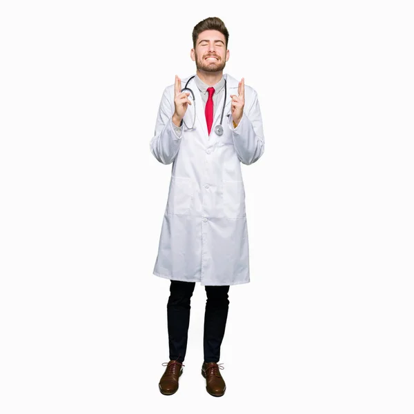 Jóképű Fiatal Orvos Ember Visel Orvosi Kabát Mosolyogva Keresztezési Ujjak — Stock Fotó