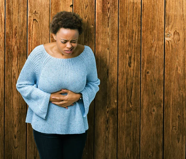 年轻美丽的非洲裔美国妇女穿着一件毛衣在孤立的背景与手在胃 因为恶心 疼痛的疾病感觉不舒服 Ache — 图库照片