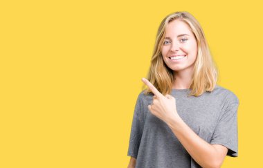 İzole arka neşeli bir gülümseme ile el ve parmak kadar yan yüzünde mutlu ve doğal ifade ile işaret yüz üzerinden büyük boy rahat t-shirt giyen güzel genç kadın