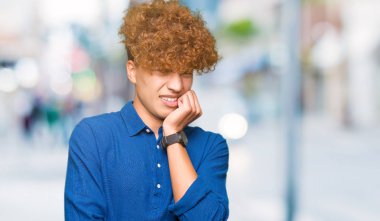 Stresli ve gergin elle çivi ısırma ağzına bakarak afro saçlı genç yakışıklı zarif adam. Anksiyete sorunu.