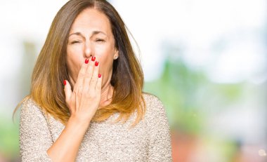 Moda kazak giyen güzel orta yaş kadın esneme yorgun kapsayan ağız el ile sıkılmış. Restless ve uyku hali.