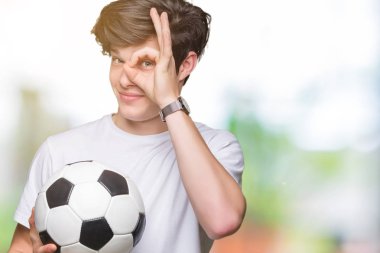 Mutlu yüz el parmaklarının arasından seyir göz üzerinde ok işaretiyle yapıyor gülümseyen izole arka plan üzerinde futbol futbol topu tutan genç adam