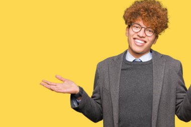 Genç yakışıklı iş adamı ile gözlük clueless ve şaşkın bir ifadeyle kollar ve eller kaldırdı giyen afro. Şüphe kavramı.