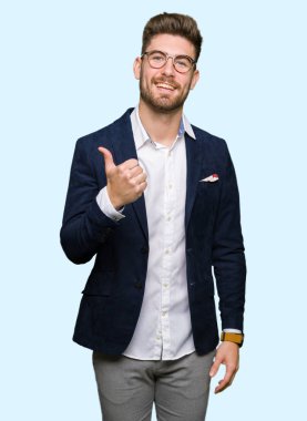 Hareketi el ile mutlu yaşasın yapıyor gözlüklü genç yakışıklı iş adamı. Kameraya bakarak başarı gösteren ile ifade onaylama.