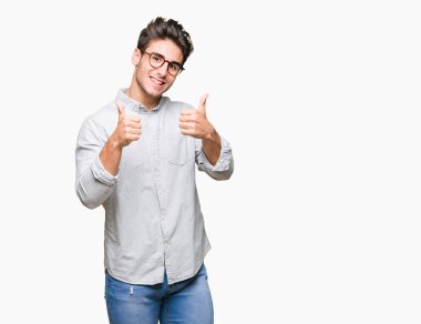 Yakışıklı delikanlı izole arka plan başarı işareti el ile pozitif jest yapıyor üzerinde gözlük takan başparmak gülümseyen ve mutlu. Neşeli bir ifadeyle, kazanan jest kameraya bakıyor.