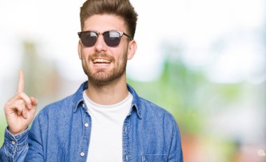 Denim ceket işaret parmağı ile başarılı fikir giyen genç yakışıklı zarif adam. Çıktıktan ve mutlu. Bir numara.