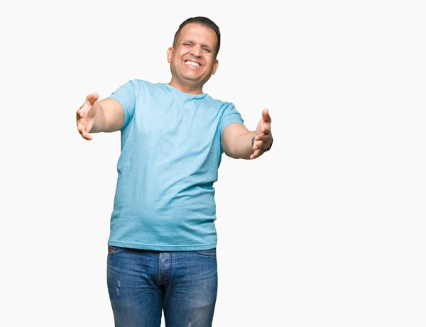 中年阿拉伯男子穿着蓝色 T恤在孤立的背景看着镜头微笑着张开双臂拥抱 拥抱幸福的快乐表情 — 图库照片