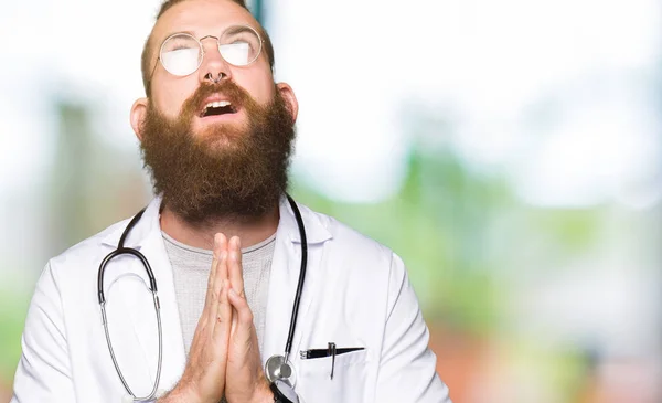 Joven Médico Rubio Con Barba Llevando Abrigo Médico Mendigando Rezando — Foto de Stock