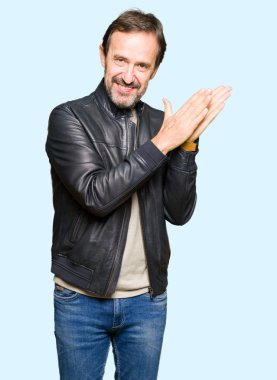 Siyah deri giyen orta yaş yakışıklı adam ceket Clapping ve mutlu ve neşeli, gururlu gülümseyen birlikte eller alkış
