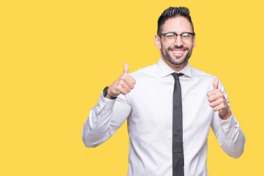 Genç yakışıklı iş adamı izole arka plan başarı işareti el ile pozitif jest yapıyor üzerinde gözlük takan başparmak gülümseyen ve mutlu. Neşeli bir ifadeyle, kazanan jest kameraya bakıyor.