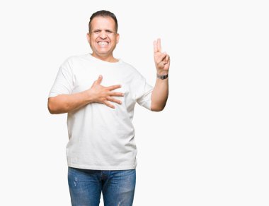 Orta yaş Arap adam wearig beyaz t-shirt üzerine izole arka plan Swearing göğüs ve parmaklar, el ile bir sadakat sözü yemin yapma
