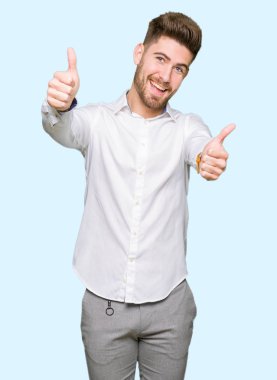 Genç yakışıklı iş adamı el ile pozitif jest yapıyor onaylama başparmak gülümseyen ve başarı için mutlu. Kamera, kazanan jest arıyorsunuz.