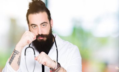 Doktor uzun saç giyen tıbbi ceket ve stetoskop ile hazır yumruk savunma hareketi, kızgın ve üzgün yüz, sorunu korkuyor ile mücadele