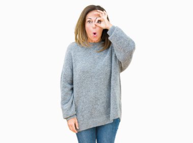 Güzel orta yaş kadın izole arka plan üzerinde kış kazak giyen sürpriz yüz, göz parmaklarıyla bakarak şok ok jest yapıyor. İnanılmaz ifade.