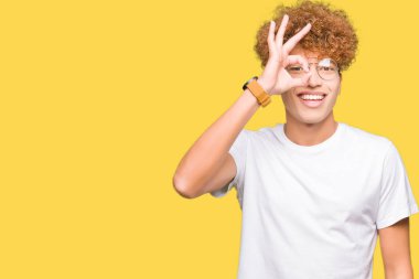 Yakışıklı delikanlı afro saçlı gözlüklü gülümseyen, parmakları ile mutlu yüz üzerinden seyir göz el ile ok jest yapıyor.