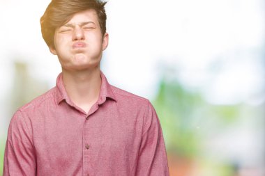 Komik surat ile yanakları şişirme izole arka plan üzerinde genç yakışıklı iş adamı. Ağız ile hava, deli ifade şişirilmiş.