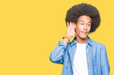Afrikalı-Amerikalı genç afro saçlı bir işitme söylenti ya da dedikodu için dinleme kulak üzerinde el ile gülümseyen. Sağırlık kavramı.