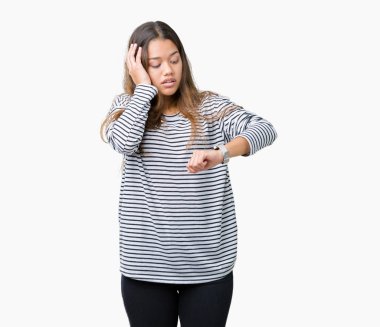 Giyen genç güzel esmer kadın çizgili süveter izole arka plan üzerinde seyretmek zaman endişeli, geç korkuyor arıyorsunuz