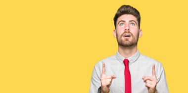 Genç yakışıklı iş adamı şaşırtmak ve yukarıya bakıp parmakları ile işaret şaşırttı ve silah kaldırdı.