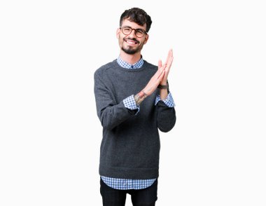 İzole arka plan üzerinde gözlük takan genç yakışıklı akıllı adam alkışlar ve mutlu ve neşeli alkışlar, gülümseyen gururlu eller birlikte