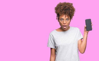 Genç Afro-Amerikan kadın gösteren smartphone ekran izole arka şok sürpriz yüzü, korkuyor ve korku ifadesi ile heyecanlı olan korkmuş üzerinde