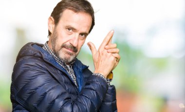 El hareketi ile sembolik silah tutan, çekim silah, kızgın yüz öldürmek oynamaya kış ceket giyen orta yaş yakışıklı adam